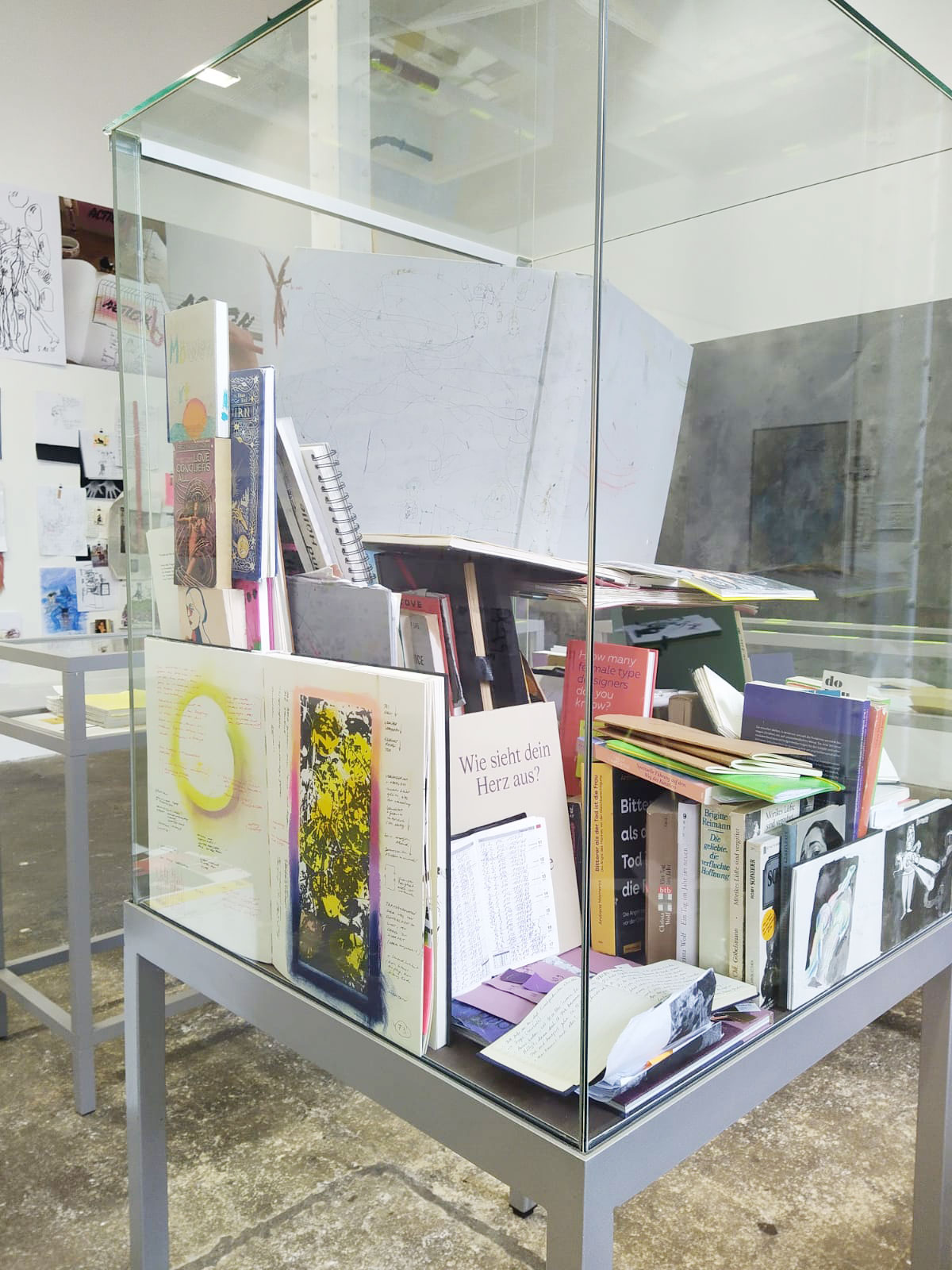 Hohe Vitrine mit einem großen Bucherstapel darin.